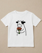 White t-shirt with a cow holding flowers design on a beige background