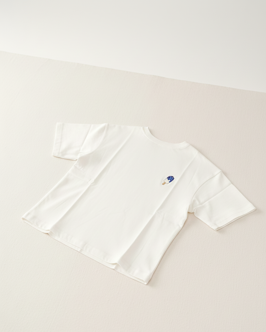 White t-shirt with a small logo on a light beige background