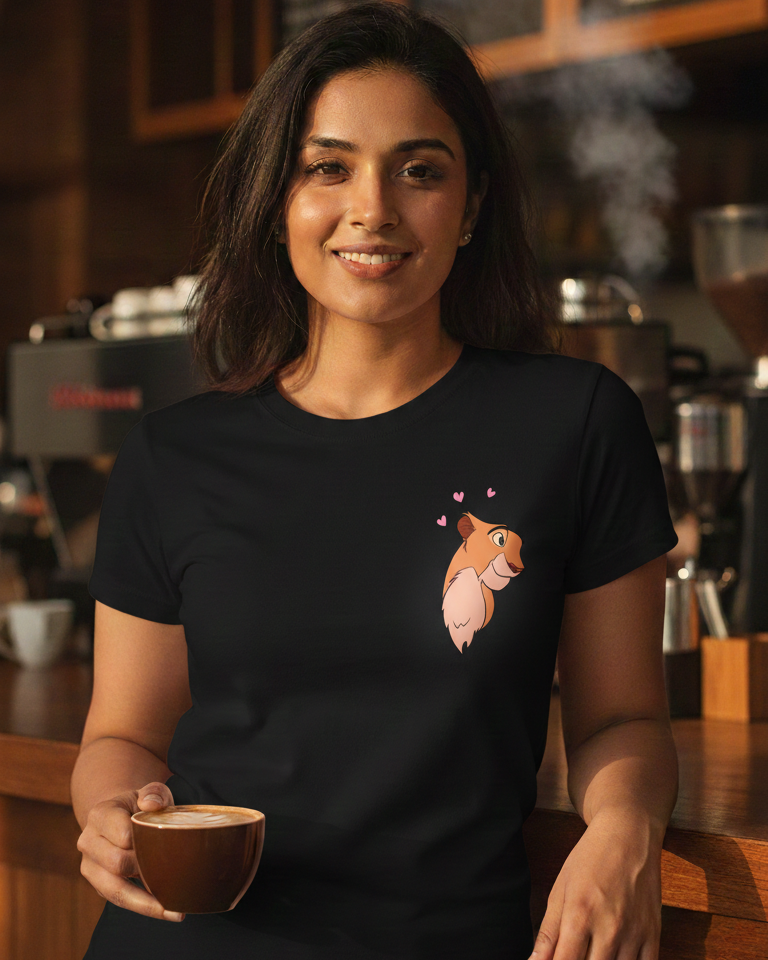 Woman holding a coffee cup in a coffee shop wearing a black t-shirt with a graphic design.