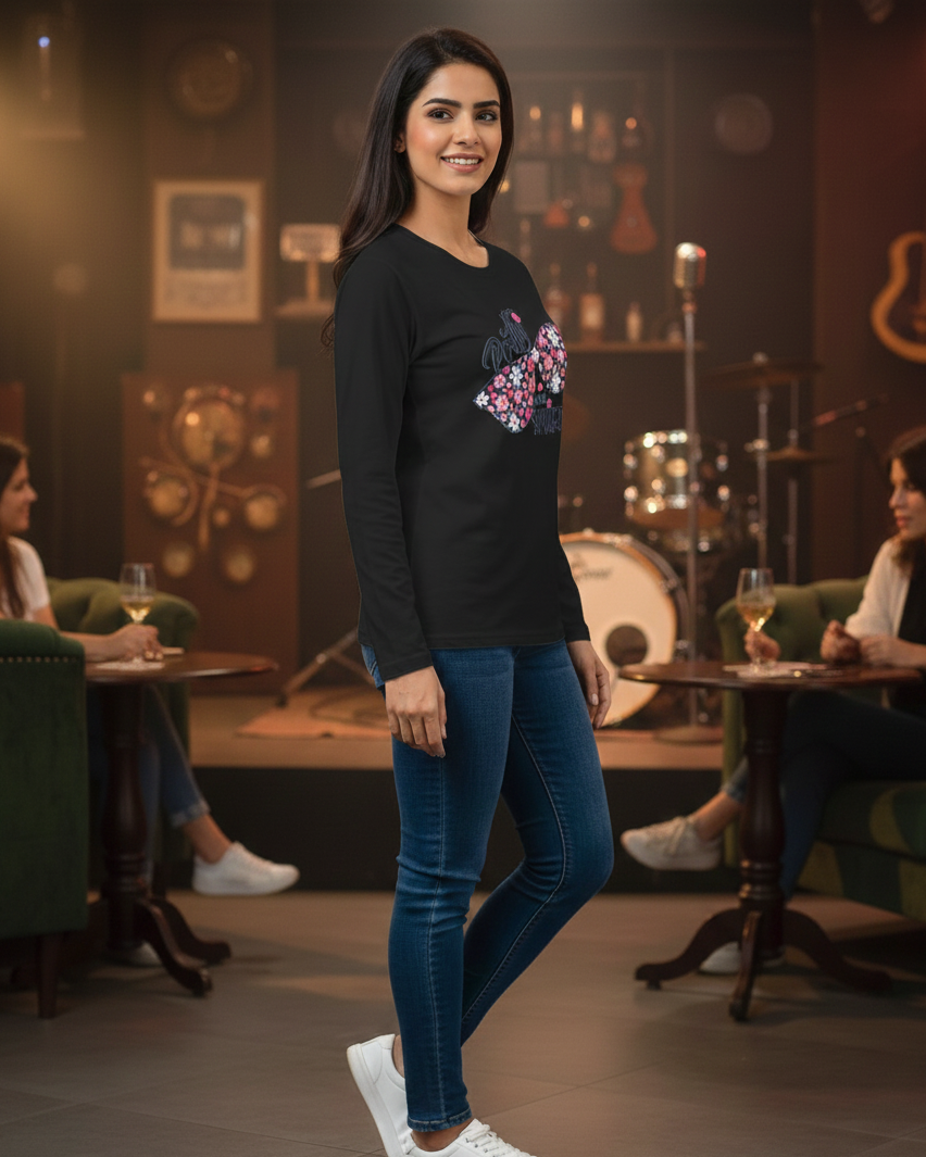 Woman in a black long-sleeve shirt with a colorful design and blue jeans standing in a bar setting.