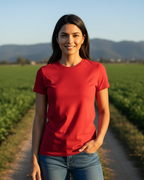 Woman in a red shirt standing in a field with mountains in the background
