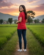 Woman in a red shirt standing in a green field with mountains in the background