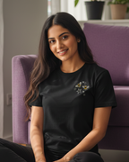 Woman sitting on the floor in a living room wearing a black t-shirt with a logo.