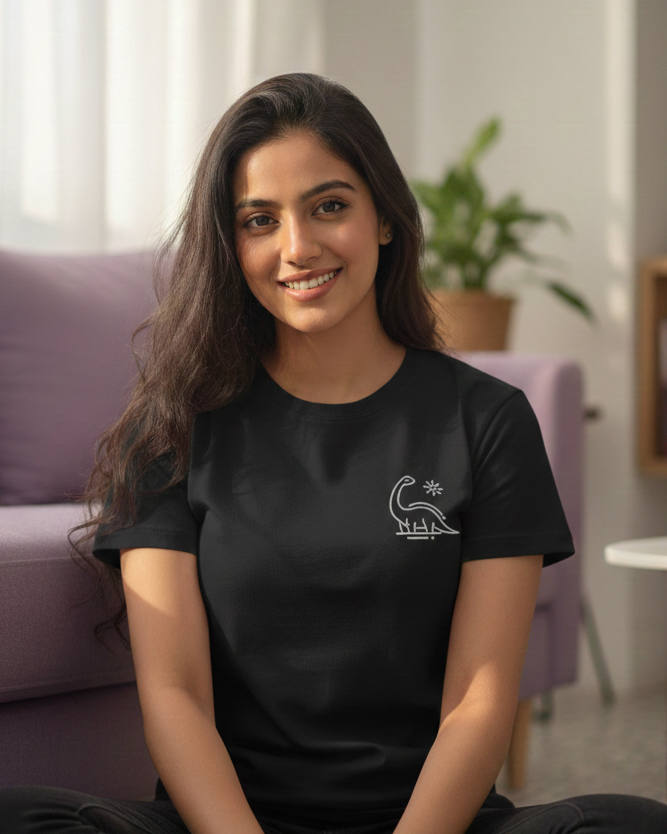 Woman sitting on the floor wearing a black t-shirt with a logo, smiling at the camera.