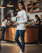 Woman standing in a coffee shop wearing a white sweatshirt with colorful text and blue jeans.