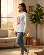 Woman standing in a living room wearing a white sweatshirt with colorful text and blue jeans.