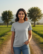 Woman standing on a dirt path in a field with trees and mountains in the background