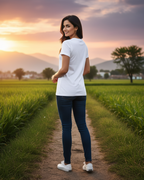 Woman standing on a path in a field with a scenic sunset background