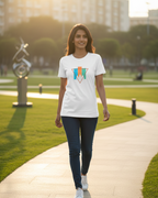 Woman walking on a path in a park wearing a white t-shirt with a geometric design.