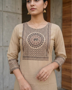 Woman wearing  beige kurta with intricate patterns in an outdoor setting