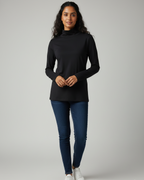 Woman wearing a black high neck and blue jeans on a gray background