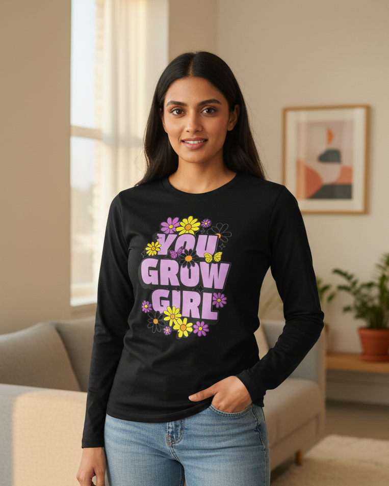 Woman wearing a black long-sleeve shirt with 'You Grow Girl' text in a living room.