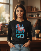Woman wearing a black long-sleeve shirt with colorful text and flamingo design in a coffee shop.