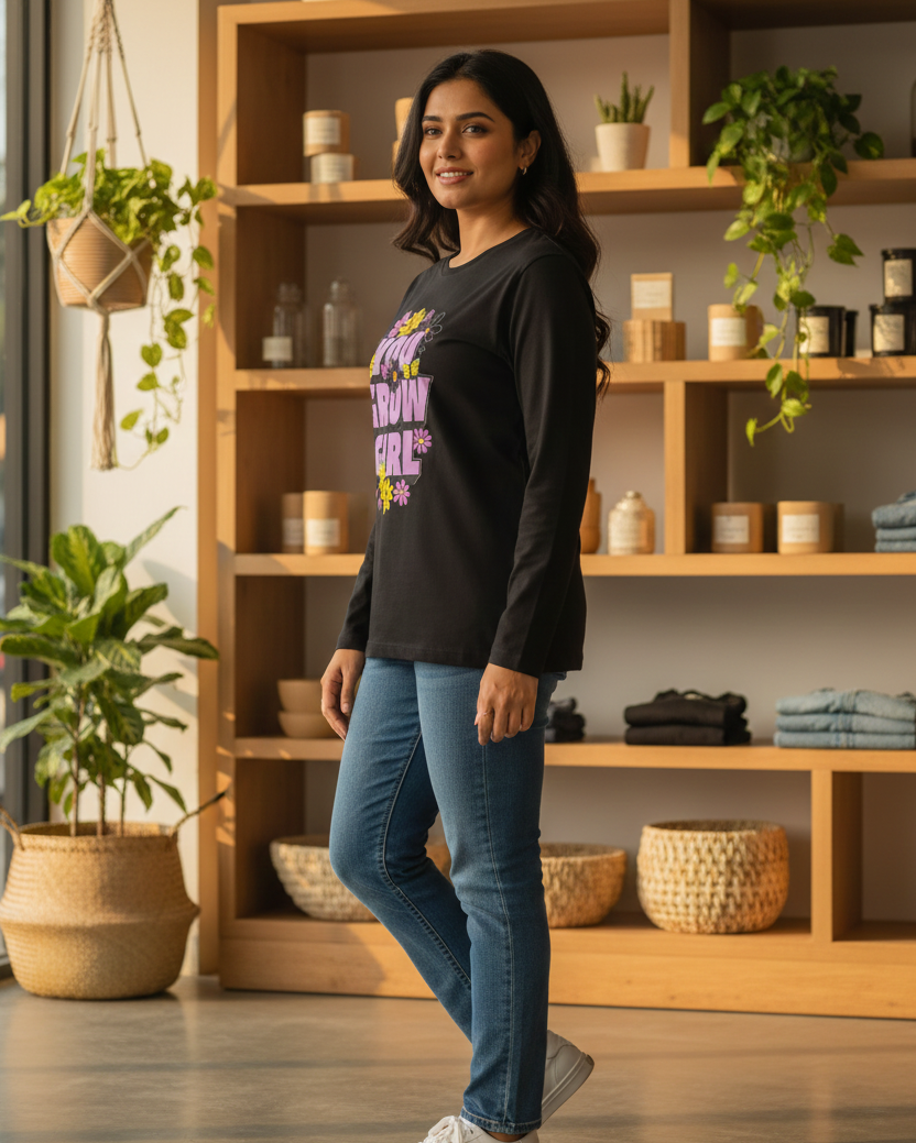 Woman wearing a black sweatshirt with colorful text in a room with wooden shelves and plants.