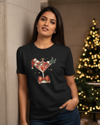 Woman wearing a black t-shirt with a Christmas-themed design in front of a decorated tree.