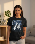 Woman wearing a black t-shirt with a bicycle graphic and text in a living room.