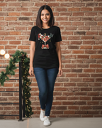 Woman wearing a black t-shirt with a graphic design in front of a brick wall with Christmas decorations.