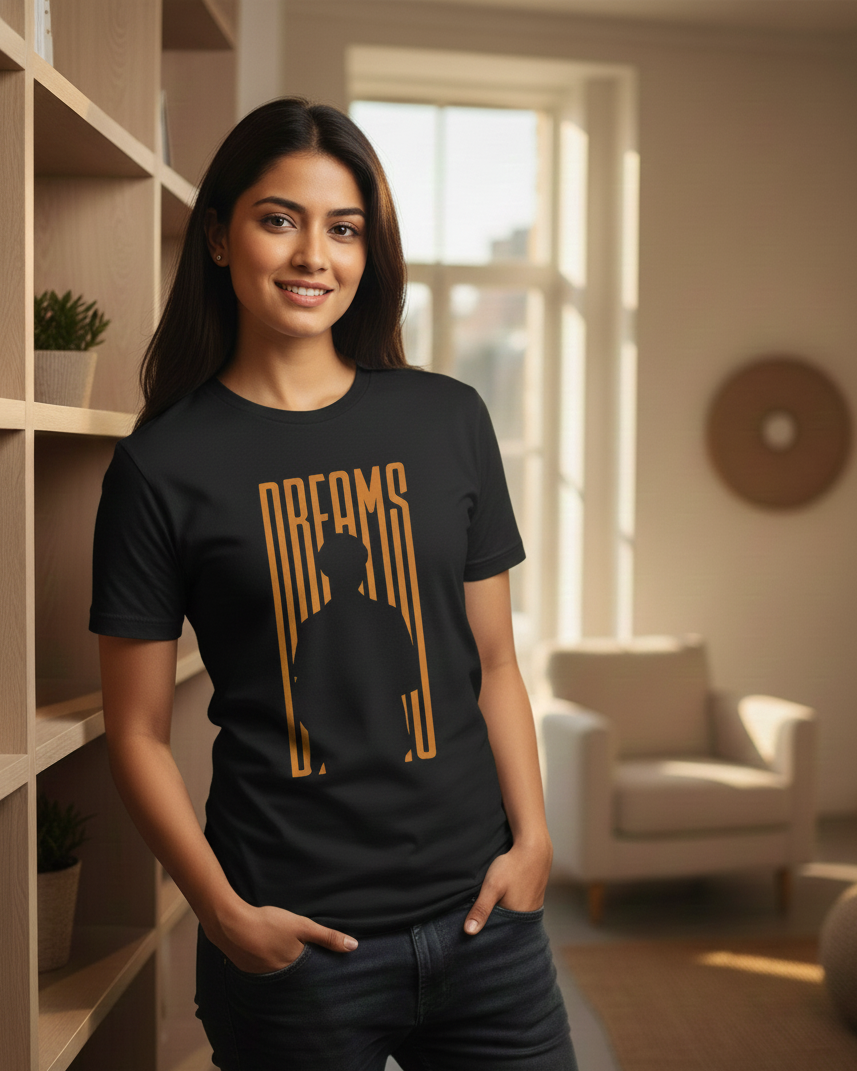 Woman wearing a black t-shirt with gold text and silhouette design in a room with shelves and a window.
