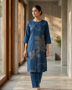 Woman wearing a blue floral dress standing in a modern indoor setting.