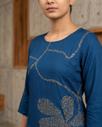 Woman wearing a blue top with floral patterns against a neutral background