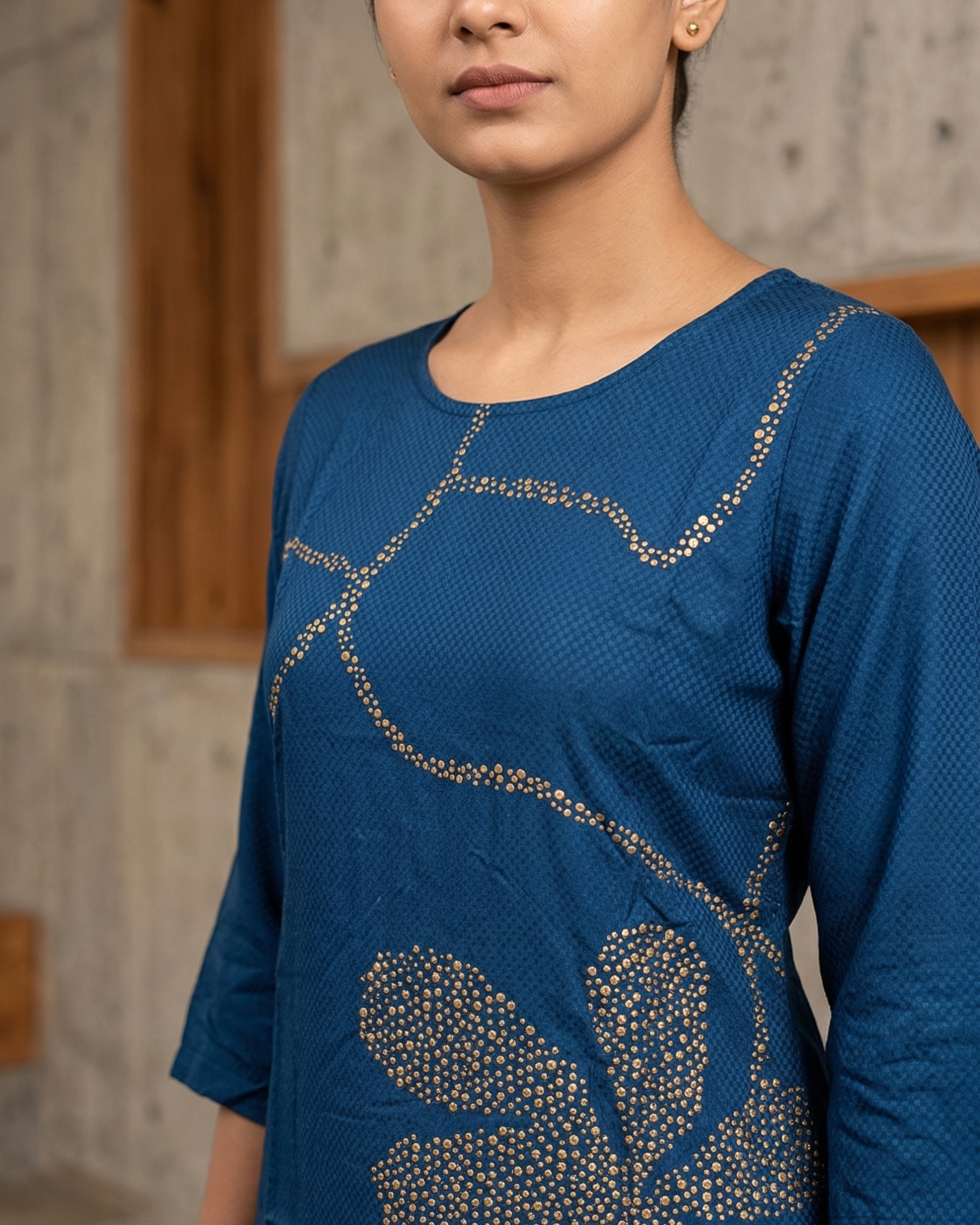 Woman wearing a blue top with floral patterns against a neutral background