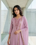 Woman wearing a pink embroidered traditional outfit in an indoor setting