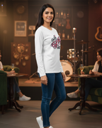 Woman wearing a white long-sleeve shirt with a colorful design and blue jeans standing in a bar setting.