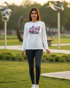 Woman wearing a white sweatshirt with floral design and text, standing in a park.