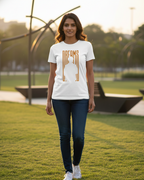 Woman wearing a white t-shirt with 'DREAMS' printed on it, standing in a park.