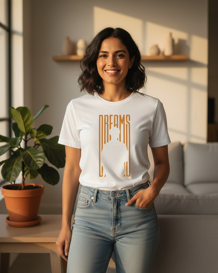 Woman wearing a white t-shirt with 'Dreams' design in a bright room.