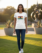 Woman wearing a white t-shirt with a graphic design, standing outdoors on grass.