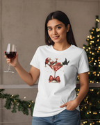 Women wearing a white t-shirt with a cocktail graphic, holding a glass of red wine, standing in front of a Christmas tree.