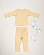 Yellow long-sleeve shirt and pants set on a white background with doodles of a hot air balloon, star, and moon.
