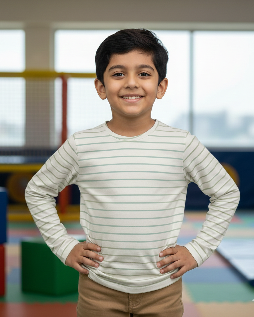 Young boy in a striped shirt standing in an indoor playground.