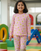 Young girl in pink pajamas with a pattern standing in a colorful playroom.