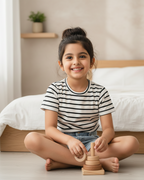 Young girl playing with a wooden toy on the floor in a bedroom.