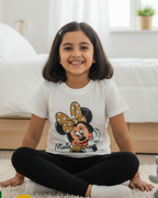 Young girl sitting on a carpeted floor in a bedroom wearing a Minnie Mouse t-shirt.