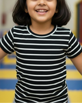 Young girl wearing a black and white striped shirt in an indoor playground.