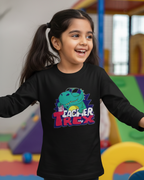 Young girl wearing a black sweatshirt with a colorful dinosaur graphic and text in an indoor playground.