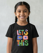Young girl wearing a black t-shirt with colorful text 'LET'S DO THIS' on a plain background