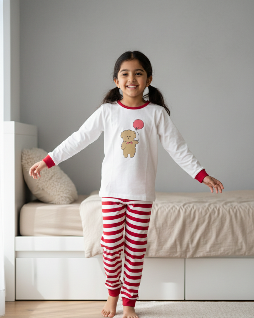 Young girl wearing a pajama set with a teddy bear design in a bedroom.