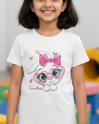 Young girl wearing a white t-shirt with a cartoon character design in a colorful indoor setting.