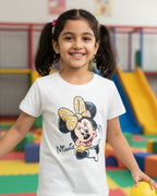 Young girl wearing a white t-shirt with a cartoon character, standing in a colorful playground.
