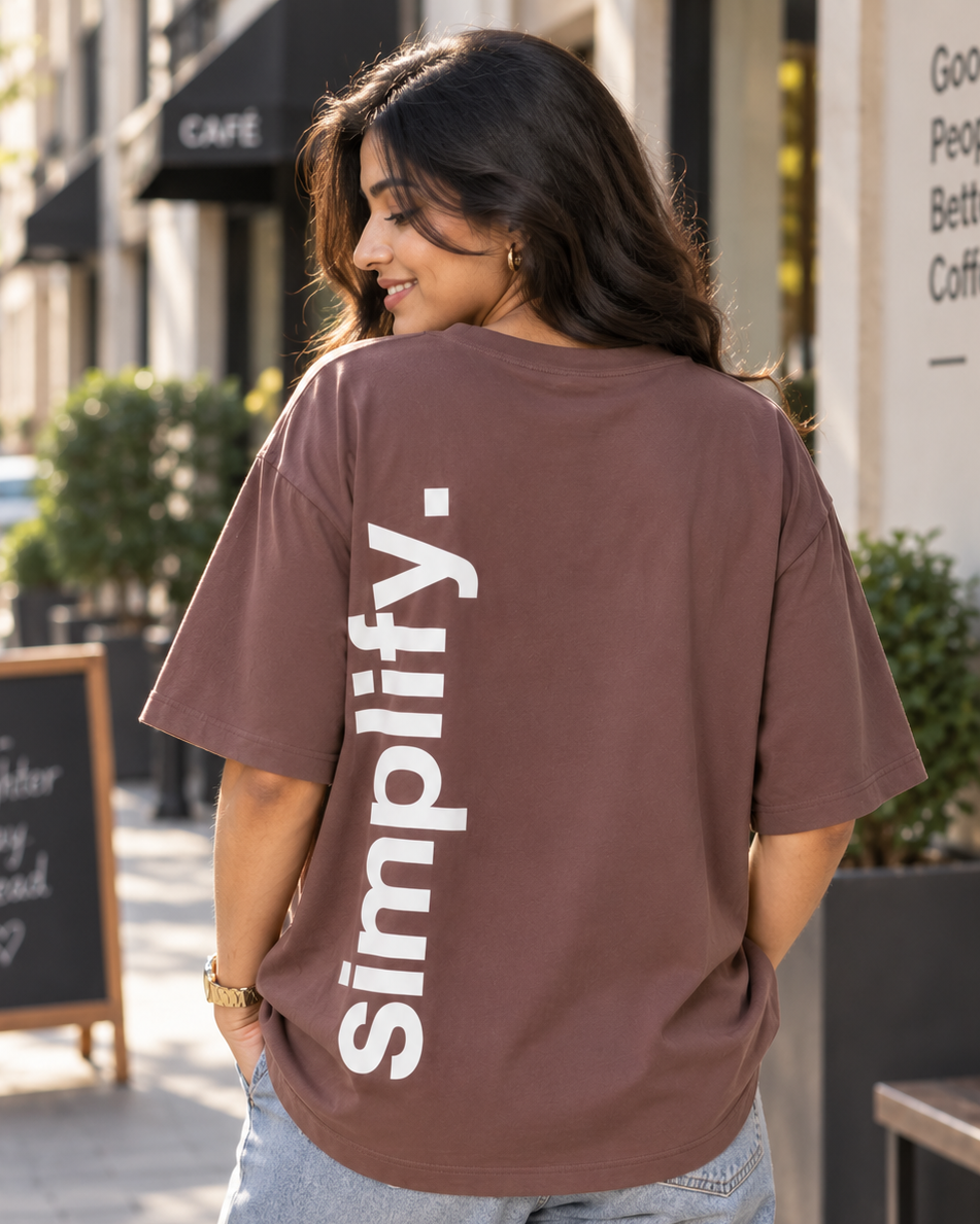 Young woman wearing “Simplify” HD print Brown Oversized T-shirt which of back pose